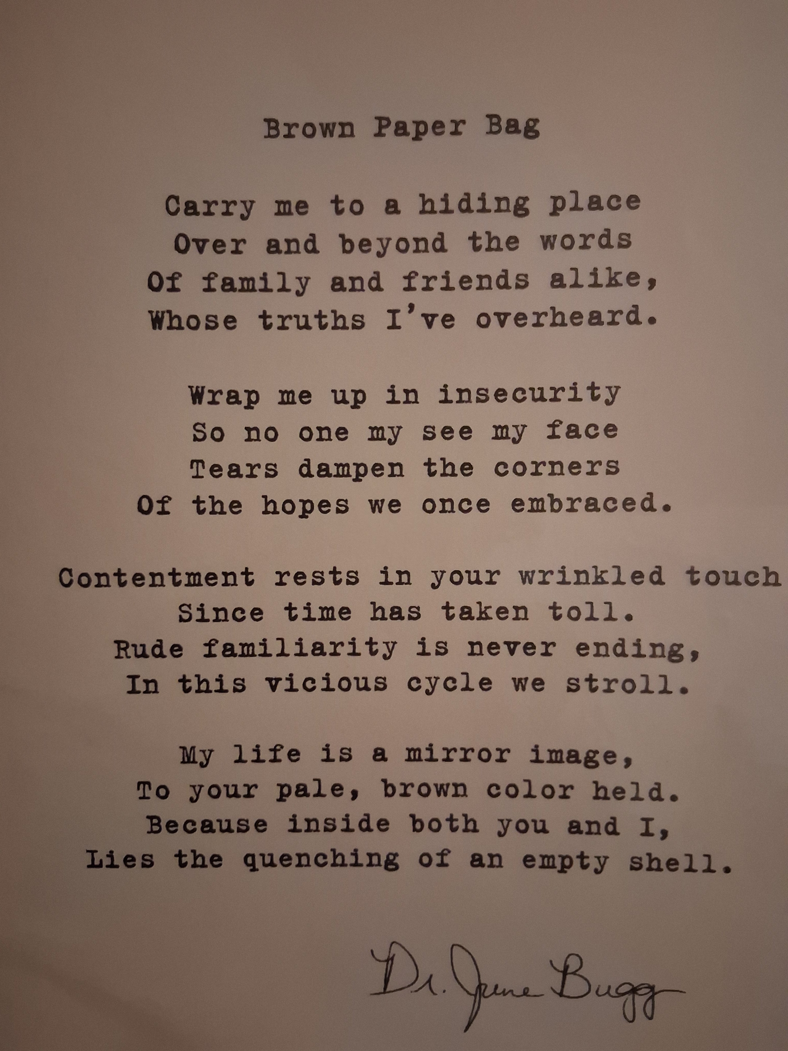 A printed poem titled 'Brown Paper Bag' on aged beige paper, with black typewriter-style text and a handwritten signature at the bottom. The author of this poem is, Eddie Wyatt, Jr. The signature is his alias name 'Dr. JuneBugg.'